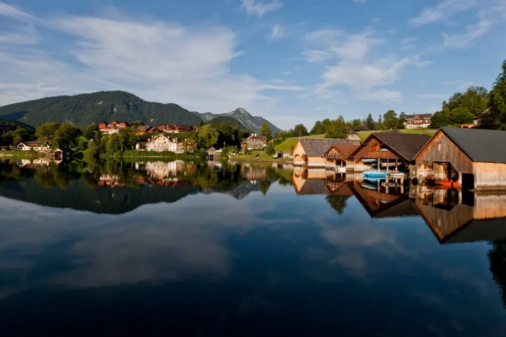 Ein See mit Häusern darauf und Bergen im Hintergrund, gelegen im Urlaub Ausseerland, Salzkammergut.