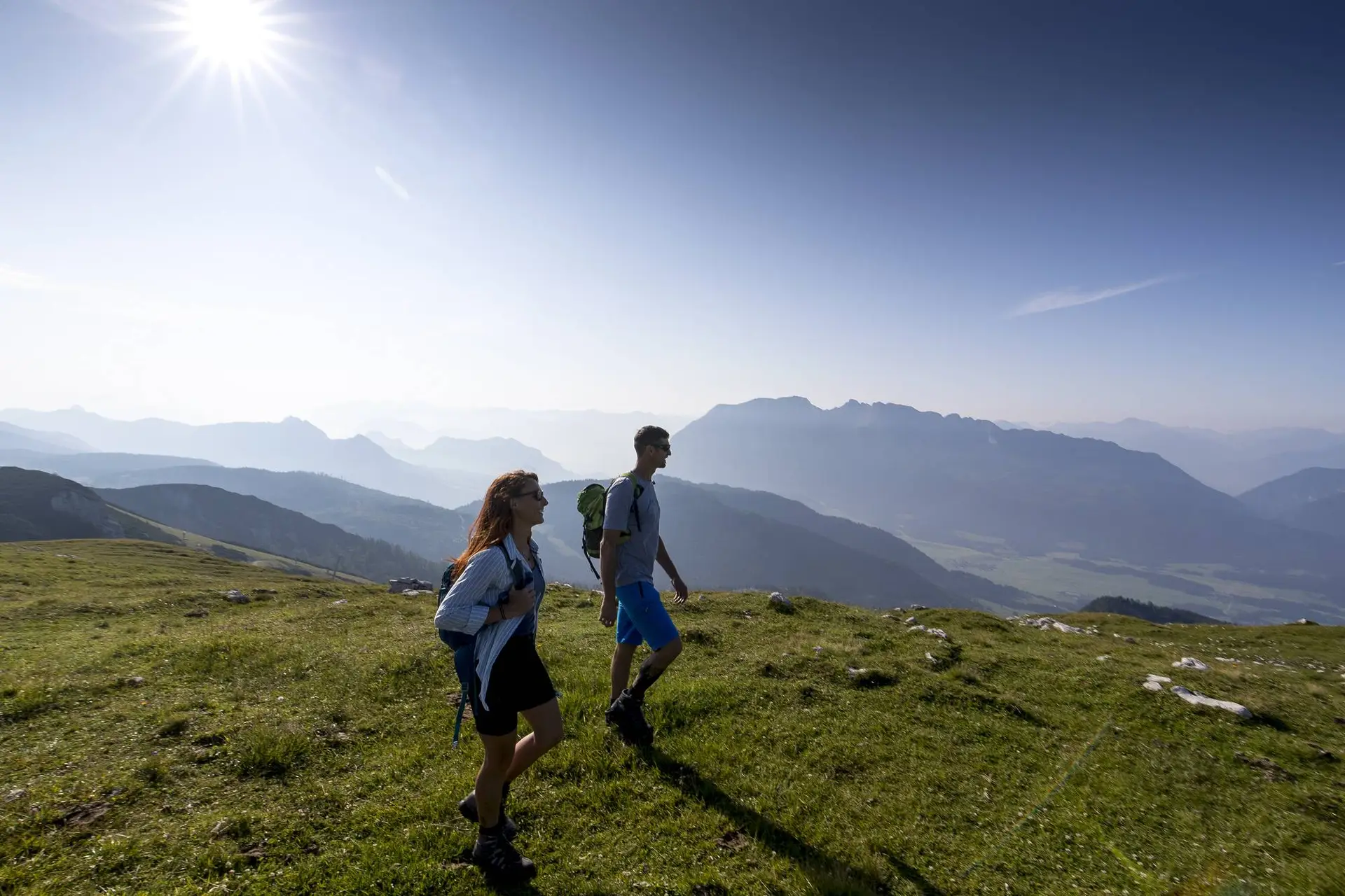 Zwei Personen wandern an einem sonnigen Tag in den Alpen und erkunden die wunderschöne Region Urlaub Österreich.